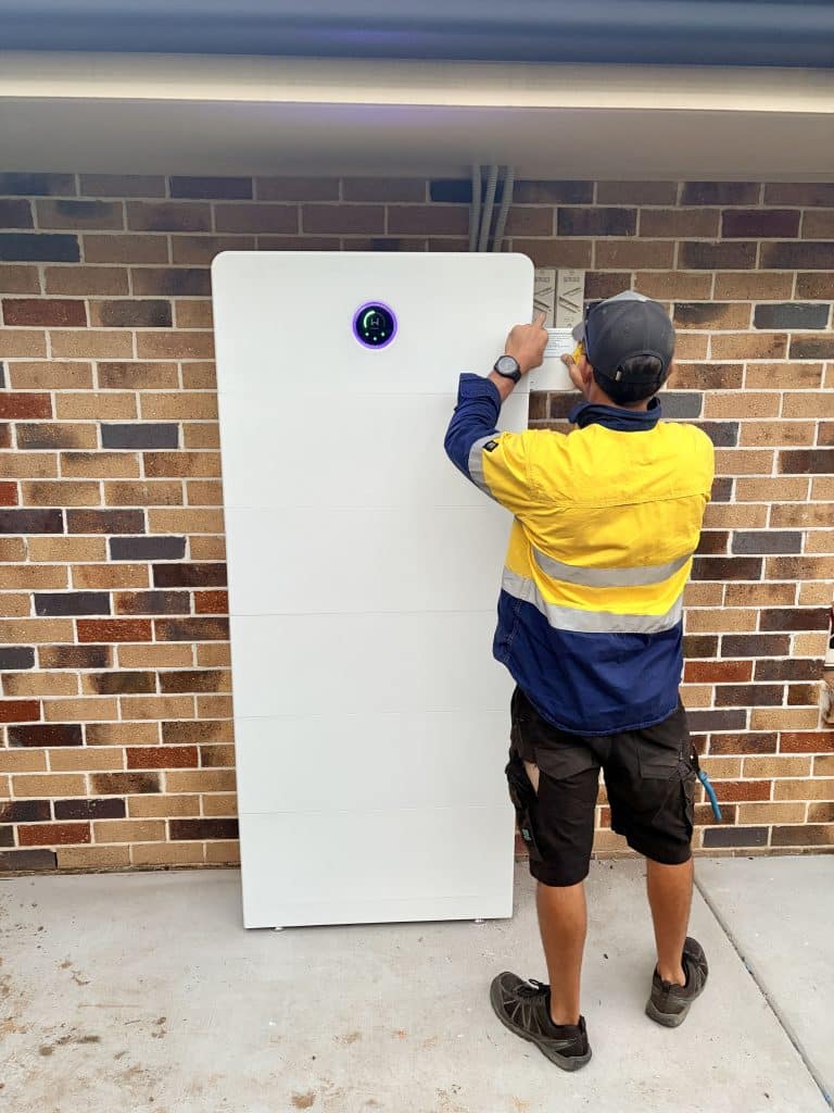 SEBSS installer fitting a home battery to a brick wall