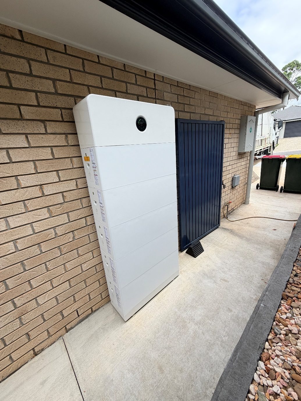 Stacked modular battery installed on an exterior brick wall next to the switchboard of a Queensland home