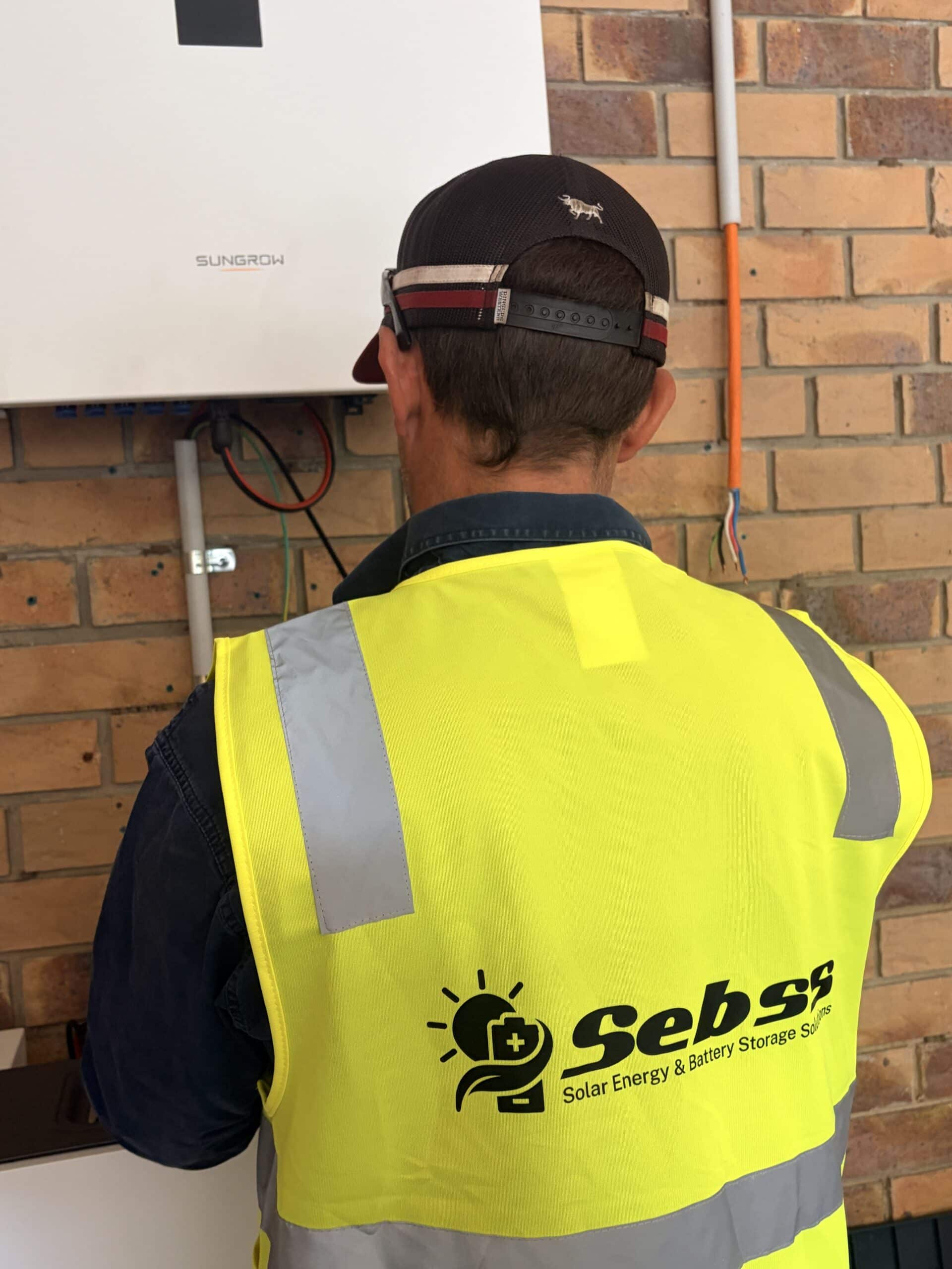 SEBSS electrician working on switchboard equipment mounted to a brick wall